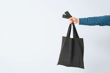 Male hand with eco bag on light background