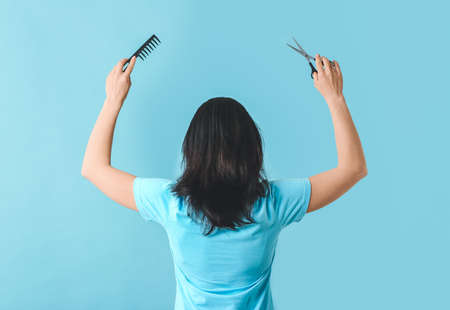Woman with hairdresser's tools on color background, back viewの写真素材