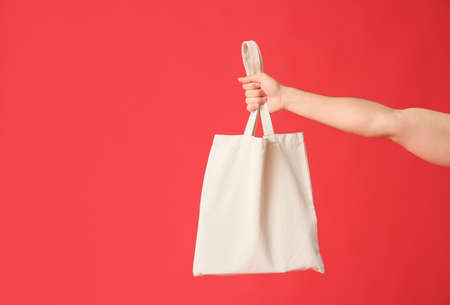 Male hand with eco bag on color background