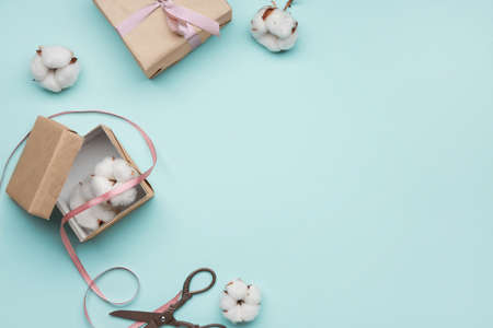 Gift boxes with beautiful cotton flowers and scissors on color backgroundの写真素材