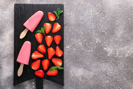 Board with tasty strawberry ice cream on gray backgroundの写真素材