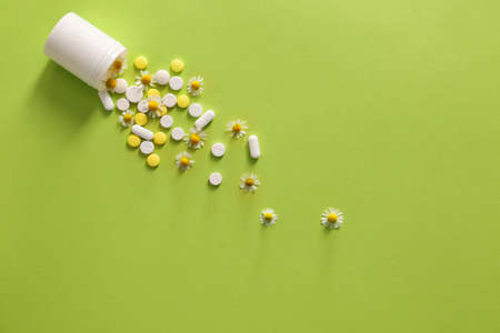 Pills with chamomile flowers on color backgroundの写真素材