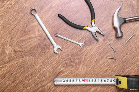 Measuring tape with builder's supplies on wooden background