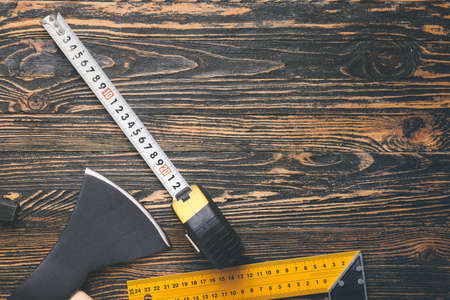 Measuring tape with builder's supplies on wooden background