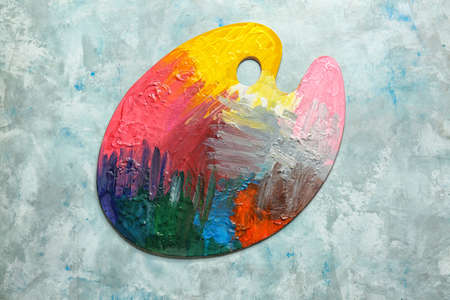 Artist's palette with paints on color background