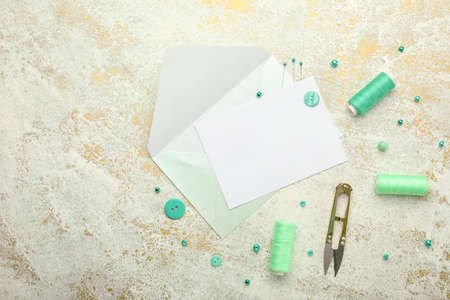 Composition with blank card, envelope and sewing supplies on light backgroundの写真素材