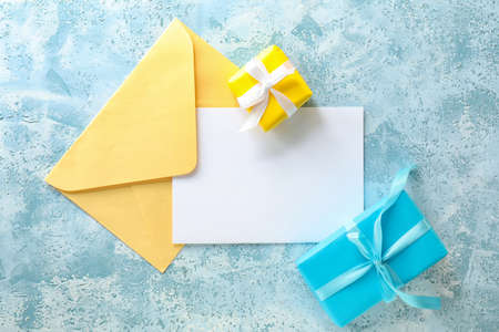 Composition with blank card, envelope and gifts on color backgroundの写真素材