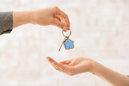 Real estate agent giving key from house to new owner indoors
