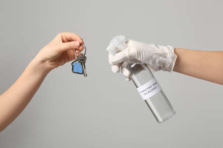 People disinfecting key from house on gray backgroundの写真素材