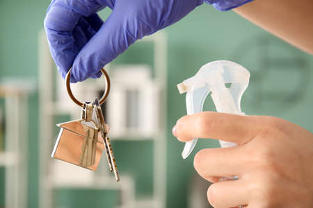 Woman disinfecting keys from house indoorsの写真素材