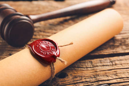 Scroll with notary public wax seal and gavel on table, closeupの写真素材