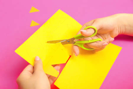 Woman with scissors cutting paper on color backgroundの写真素材