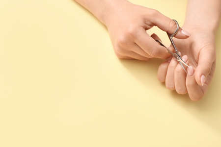 Young woman with scissors doing manicure on color backgroundの写真素材