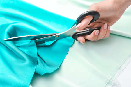 Hand of tailor cutting cloth on light backgroundの写真素材