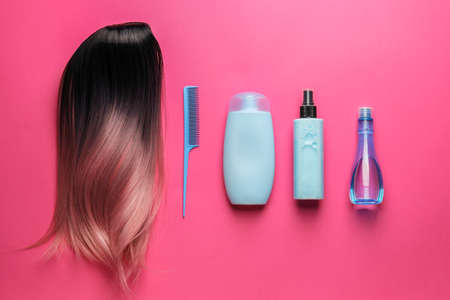 Unusual wig, comb and cosmetics for hair care on color backgroundの写真素材