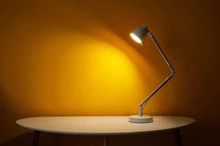 Glowing lamp on table in dark roomの写真素材