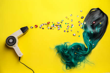 Unusual wig with blow dryer and gemstones on color backgroundの写真素材