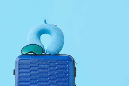 Packed suitcase and travel pillow with sleep mask on color backgroundの写真素材