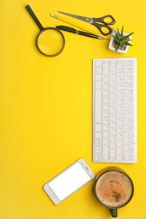 Different stationery with mobile phone, computer keyboard and cup of coffee on color backgroundの写真素材