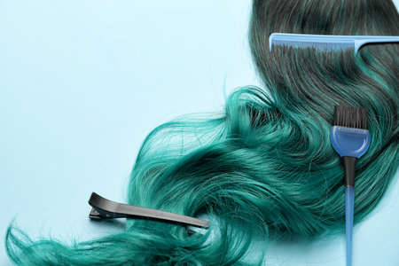 Unusual wig with hairdresser supplies on color backgroundの写真素材