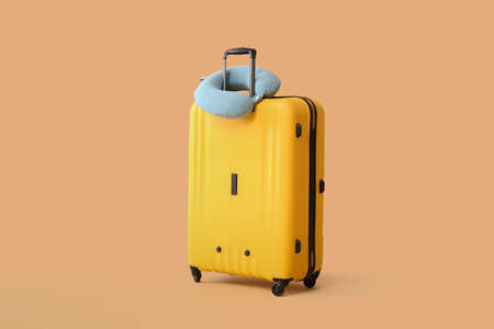 Packed suitcase and travel pillow on color backgroundの写真素材