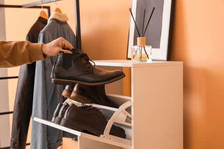 Man taking shoes from stand in hallの写真素材