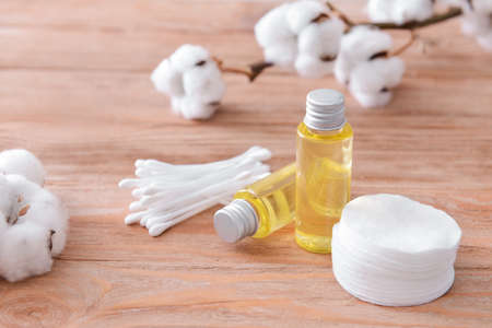 Bottles of cottonseed oil with cosmetic pads and swabs on table