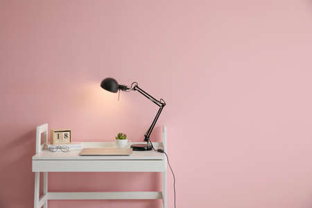 Glowing lamp and laptop on table in roomの写真素材