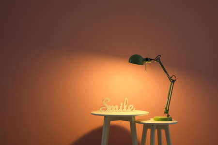 Glowing lamp and tables near color wallの写真素材