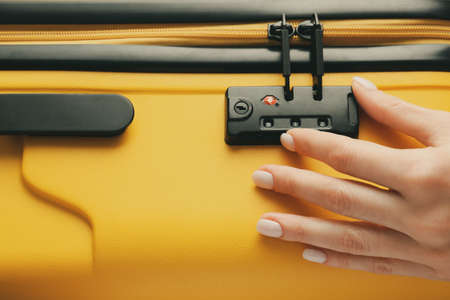 Woman opening lock on suitcase, closeupの写真素材