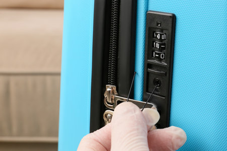 Male thief trying to open stolen suitcase, closeupの写真素材