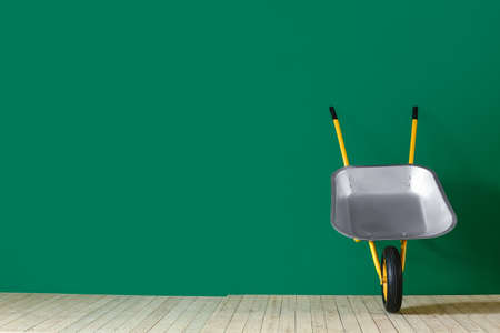 Empty wheelbarrow near color wallの写真素材
