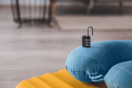 Suitcase with lock and travel pillow in room, closeup