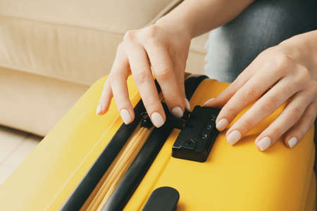 Woman opening lock on suitcase, closeupの写真素材