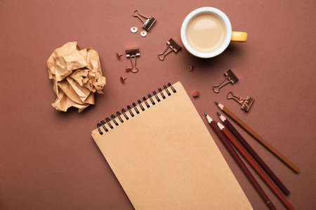 Office supplies with cup of coffee on color background