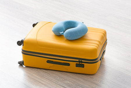 Packed suitcase and travel pillow on floorの写真素材