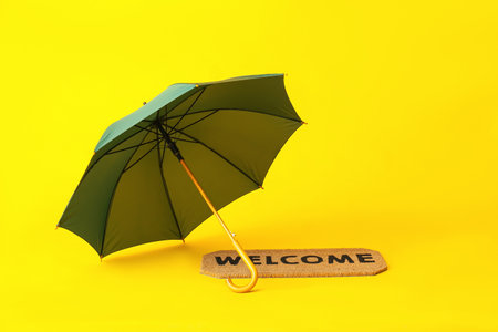 Stylish umbrella and door mat on color backgroundの写真素材