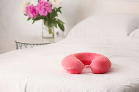 Travel pillow on bed in roomの写真素材