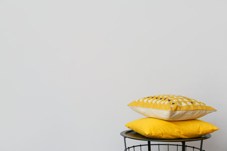 Table with soft cushions near light wall in roomの写真素材