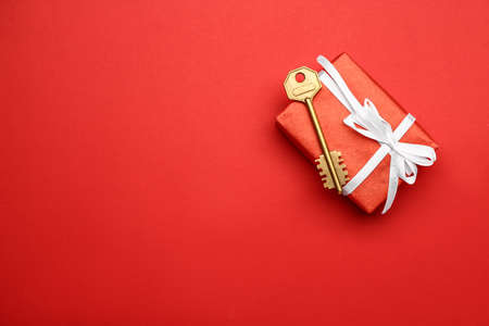 Gift box with key on color background