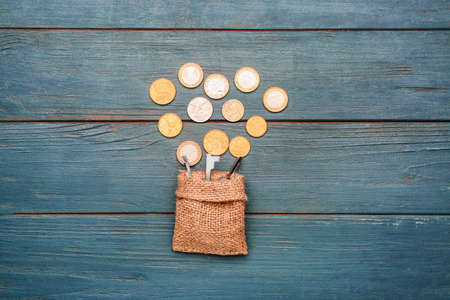 Bag with keys and coins on wooden background