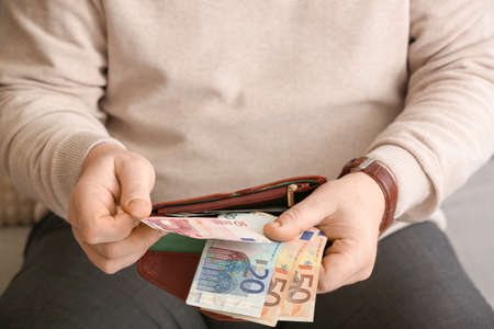 Senior man counting money at home, closeup
