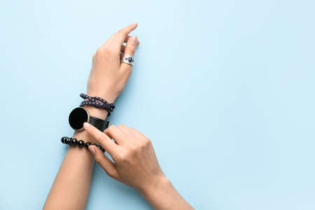 Female hands with stylish wrist watch on color backgroundの写真素材