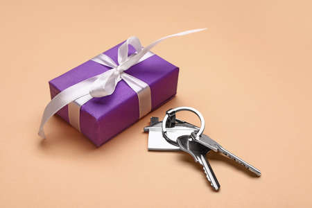 Gift box with keys from house on color background