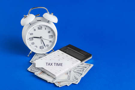 Alarm clock with calculator and money on color background. Concept of tax deadline