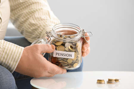 Senior man with savings in jar at homeの写真素材