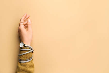 Female hand with stylish wrist watch on color backgroundの写真素材