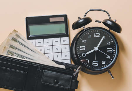 Alarm clock with calculator and money on color background