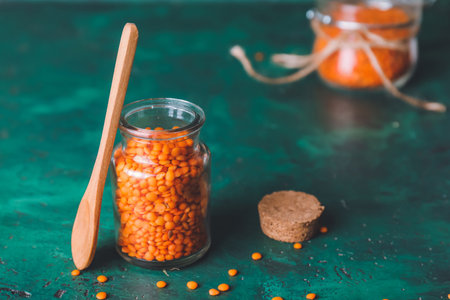 Jar with red lentils and spoon on color backgroundの写真素材