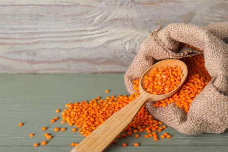 Bag and spoon with red lentils on table